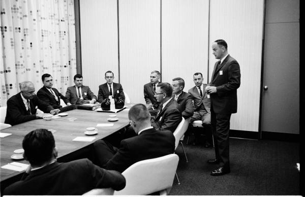 Black and white period IBM photo showing men in dark suits and white shirts.